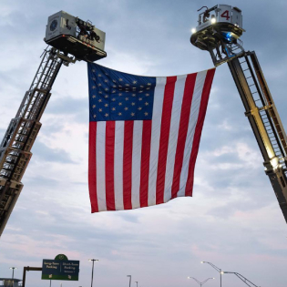 American flag hanging from fire truck ladders