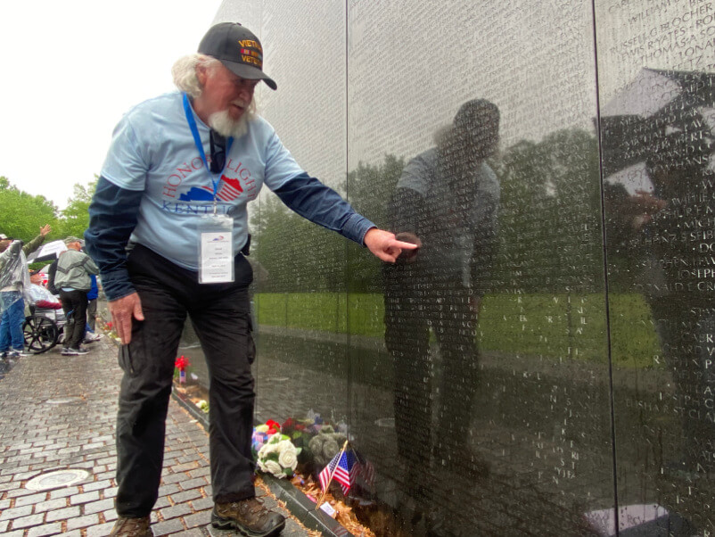 Veteran pointing at names on memorial wall